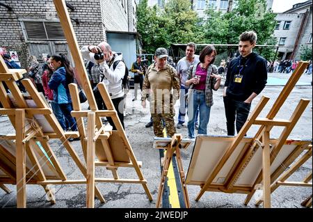 ZAPORIZHZHIA, UKRAINE - 04. SEPTEMBER 2022 - die Besucher sehen sich die Kunstwerke an, die während des Ausstellungsverkaufs zur Unterstützung der gefangenen Verteidiger von Asowstal, Zaporizhzhia, Südost-Ukraine, präsentiert wurden. Stockfoto