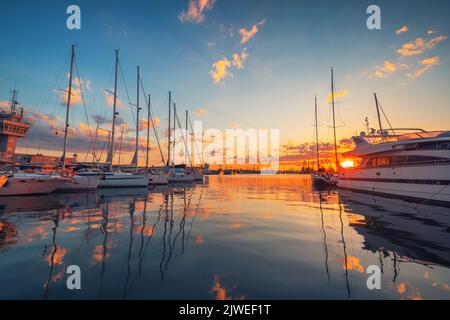 Jacht- und Segelboothafen und schöner Sonnenuntergang über dem Meer. Yachten und Boote an der Küste. Stockfoto