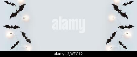 Halloween-Urlaub. Halloween Banner mit schwarzen Papierfledermäusen und heller Girlande mit Geistern auf blauem Hintergrund mit Kopierraum. Flach liegend, Bannergröße Stockfoto
