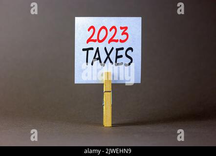 2023 Steuern Neujahr Symbol. Weißes Papier mit Worten 2023 Steuern, Clip auf Holzlasche. Schöne graue Tabelle grauen Hintergrund. Business und 2023 Steuern Stockfoto
