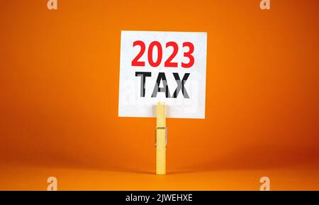 Symbol für 2023 Steuern für das neue Jahr. Weißes Papier mit Worten 2023 Steuer, Clip auf Holzlasche. Schöne orange Tisch orange Hintergrund. Business und 2023 Steuern Stockfoto