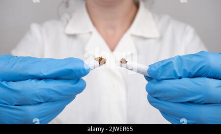 Hört auf zu rauchen, eine defekte Zigarette in den Händen eines Arztes. Stockfoto