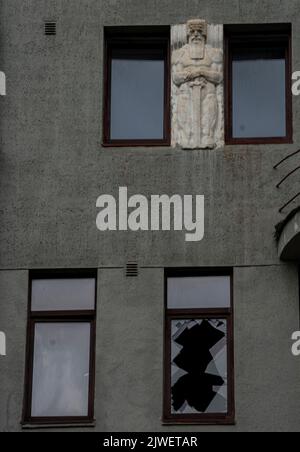 Blick auf ein Charkiw-Gebäude mit einem Basrelief eines Kriegers und einem zerbrochenen Fenster als Folge eines russischen Raketenangriffs Stockfoto