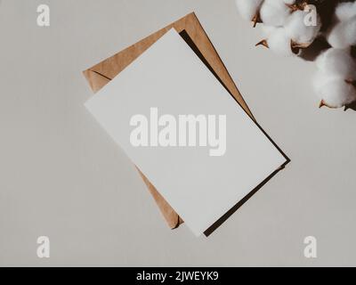 Leere weiße Karte, Umschlag und Zweigteil auf hellgrauem Hintergrund, Draufsicht. Design-Element für Hochzeitseinladung, Dankeskarte, Begrüßung, Geschäft Stockfoto