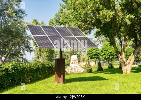 Sonnenkollektoren im öffentlichen Park im Hintergrund. Photovoltaikmodule für erneuerbare Energien, System von elektrischen Generatoren aus der Sonne. Saubere Technologien, gree Stockfoto