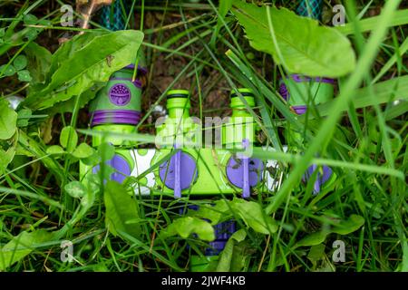 Auf dem grünen Gras liegt ein Kunststoffsplitter für die Bewässerung von Schläuchen. Stockfoto