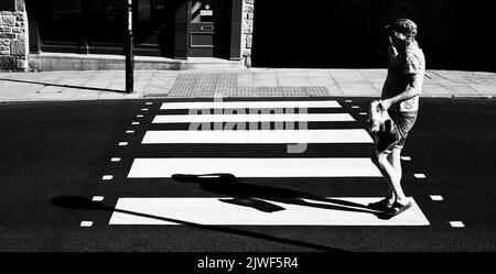 Eine Person, die auf einer brandneuen Zebrakreuzung die Straße überquert Stockfoto