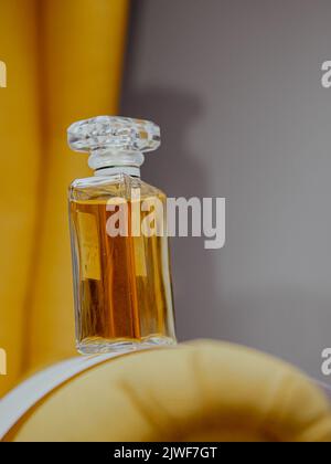 Eine vertikale Aufnahme einer ästhetischen, klaren Parfümflasche mit Goldsubstanz Stockfoto