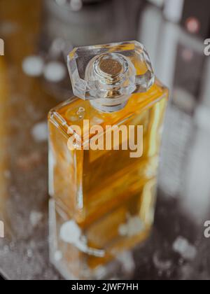 Eine vertikale Aufnahme einer ästhetischen, klaren Parfümflasche mit Goldsubstanz Stockfoto