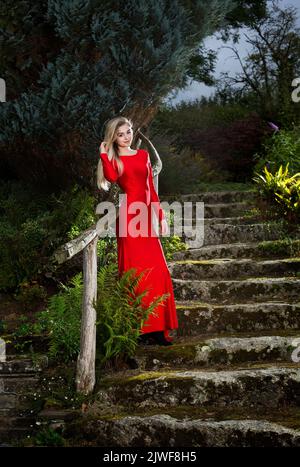 Ein junger blonder Teenager in einem roten Abendkleid Stockfoto