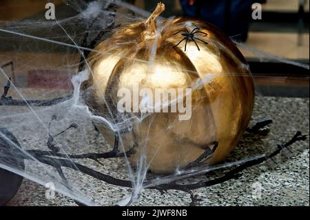 Halloween-Metallkürbis mit künstlicher Spinne und Netz Stockfoto