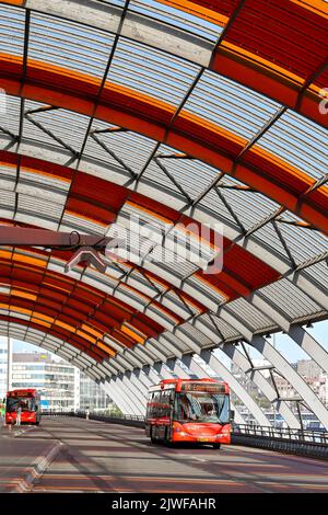 Amsterdam, Niederlande - August 2022: Öffentliche Busse verlassen den Busbahnhof unter seinem geschwungenen Dach am Amsterdam Centraal. Stockfoto