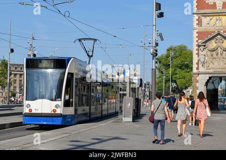 Amsterdam, Niederlande - August 2022: Moderne elektrische Straßenbahn an einer Straßenbahnhaltestelle vor dem Hauptbahnhof der Stadt Stockfoto