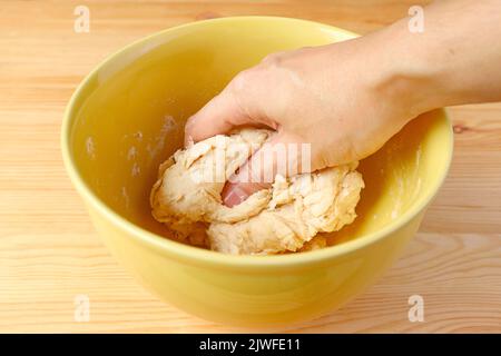 Brotteig von Hand in einer Rührschüssel kneten Stockfoto