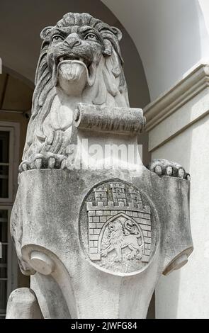 Nahaufnahme der Steinskulptur des sitzenden Löwen mit der Stadt Lemberg antikes Wappenhaus am Eingang des Rathauses, Ukraine Stockfoto