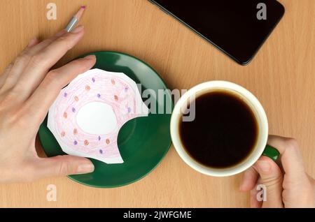 Eine Tasse Kaffee und ein bemalter Donut auf einer Untertasse. Das Konzept des Mangels an Nahrung oder Geld Stockfoto