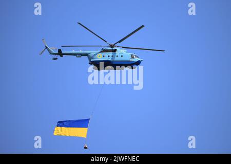 Militärhubschrauber MI-14 fliegt mit der großen Flagge der Ukraine Stockfoto