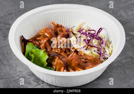 SCHÜSSEL mit Schweinefleisch gezogen, Soße und Cole Slaw Salat. In einem Kunststoff-Container zum Mitnehmen Stockfoto