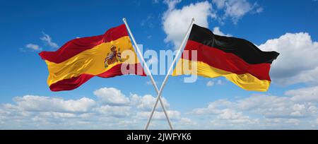 Zwei gekreuzte Flaggen Bundesrepublik Deutschland und spanien winken im Wind bei bewölktem Himmel. Konzept der Beziehung, des Dialogs, des Reisens zwischen zwei Ländern Stockfoto