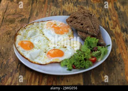Ein Teller mit suuny Seite nach oben Eier auf einem Holztisch. Stockfoto