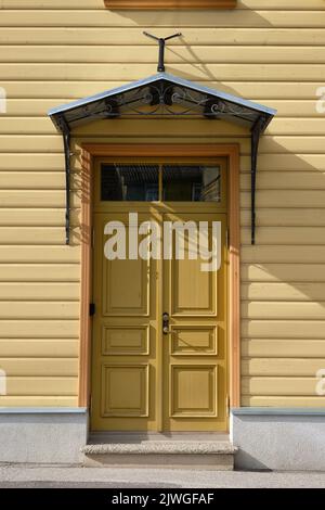 Alte senffarbene Holztüren, Eingang zum Holzhaus mit gelber Farbe an den Wänden in Tartu, Estland. Stockfoto