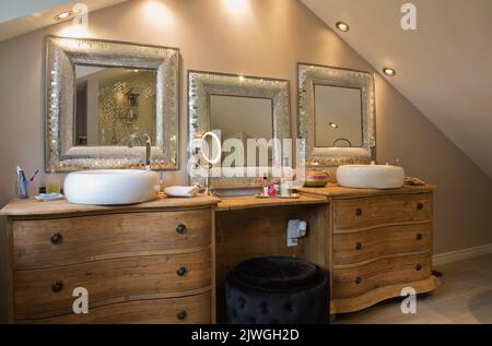 Hauptbadezimmer mit Holzschränken und silberumrahmten Spiegeln im luxuriösen Haus. Stockfoto