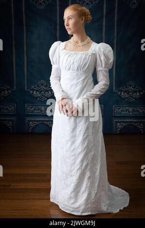 Eine Regency-Frau, die ein weißes, besticktes Musselin-Kleid mit Perlenkette trägt Stockfoto