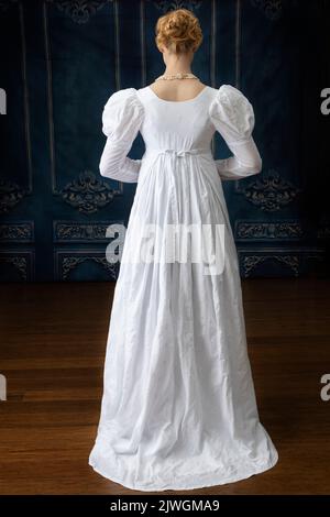 Eine Regency-Frau, die ein weißes, besticktes Musselin-Kleid mit Perlenkette trägt Stockfoto