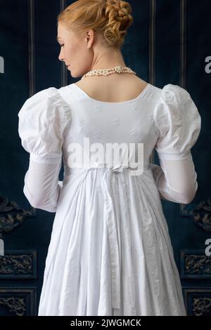 Eine Regency-Frau, die ein weißes, besticktes Musselin-Kleid mit Perlenkette trägt Stockfoto