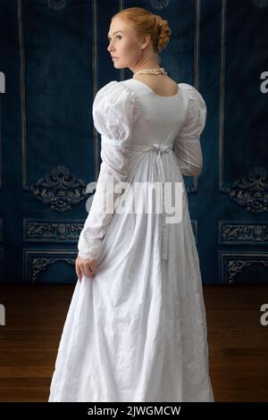 Eine Regency-Frau, die ein weißes, besticktes Musselin-Kleid mit Perlenkette trägt Stockfoto