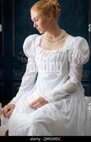 Eine Regency-Frau, die ein weißes, besticktes Musselin-Kleid mit Perlenkette trägt Stockfoto