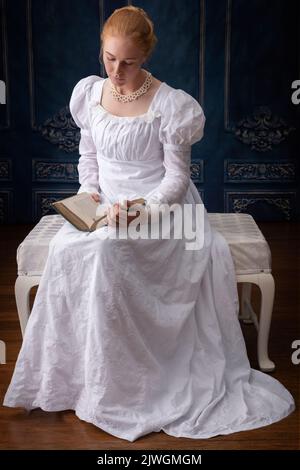 Eine Regency-Frau, die ein weißes, besticktes Musselin-Kleid mit Perlenkette trägt Stockfoto