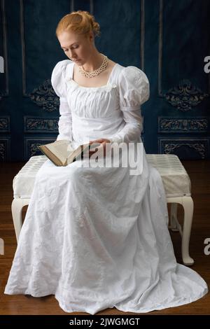 Eine Regency-Frau, die ein weißes, besticktes Musselin-Kleid mit Perlenkette trägt Stockfoto