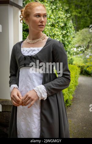 Eine Regency-Frau, die ein weißes, besticktes Musselin-Kleid mit einem langen spencer über der Oberseite trägt Stockfoto