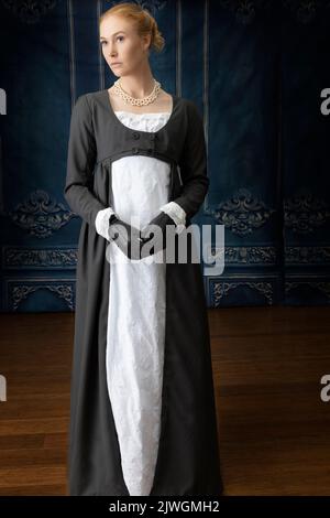 Eine Regency-Frau, die ein weißes, besticktes Musselin-Kleid mit einem langen spencer über der Oberseite trägt Stockfoto