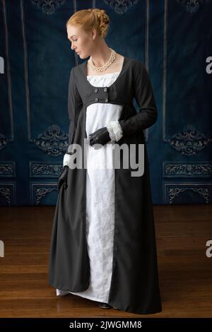 Eine Regency-Frau, die ein weißes, besticktes Musselin-Kleid mit einem langen spencer über der Oberseite trägt Stockfoto