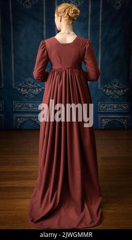 Eine Regency-Frau, die ein weißes, besticktes Musselin-Kleid mit einem langen spencer über der Oberseite trägt Stockfoto