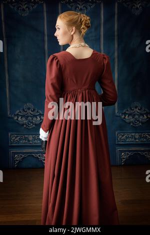Eine Regency-Frau, die ein weißes, besticktes Musselin-Kleid mit einem langen spencer über der Oberseite trägt Stockfoto