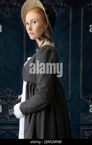 Eine Regency-Frau, die ein weißes, besticktes Musselin-Kleid mit einem langen spencer über der Oberseite trägt Stockfoto