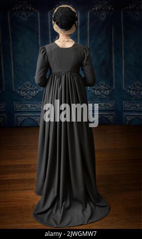 Eine Regency-Frau, die ein weißes, besticktes Musselin-Kleid mit einem langen spencer über der Oberseite trägt Stockfoto