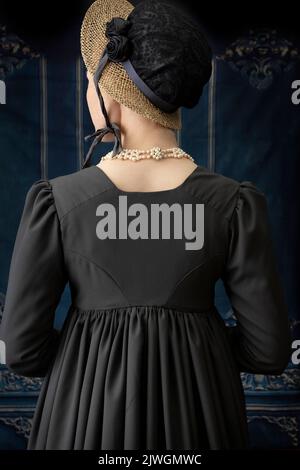 Eine Regency-Frau, die ein weißes, besticktes Musselin-Kleid mit einem langen spencer über der Oberseite trägt Stockfoto