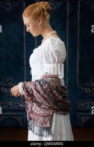 Eine Regency-Frau, die ein weißes, besticktes Musselin-Kleid mit Perlenkette trägt Stockfoto