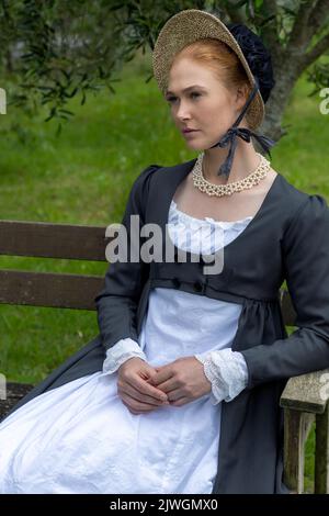 Eine Regency-Frau, die ein weißes, besticktes Musselin-Kleid mit einem langen spencer über der Oberseite trägt Stockfoto