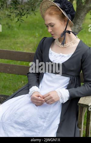 Eine Regency-Frau, die ein weißes, besticktes Musselin-Kleid mit einem langen spencer über der Oberseite trägt Stockfoto