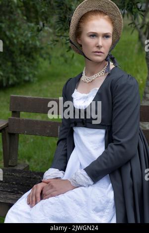 Eine Regency-Frau, die ein weißes, besticktes Musselin-Kleid mit einem langen spencer über der Oberseite trägt Stockfoto