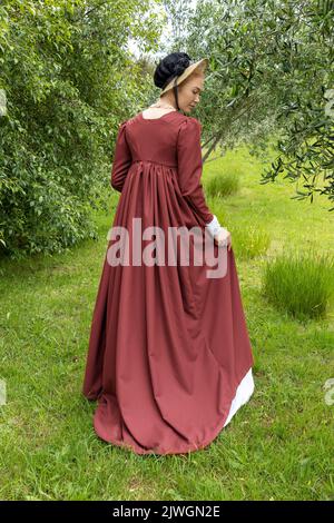 Eine Regency-Frau, die ein weißes, besticktes Musselin-Kleid mit einem langen spencer über der Oberseite trägt Stockfoto