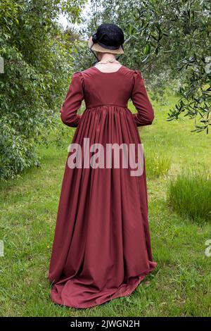 Eine Regency-Frau, die ein weißes, besticktes Musselin-Kleid mit einem langen spencer über der Oberseite trägt Stockfoto