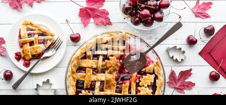 Herbstlicher Gitterkirschkuchen mit einer Scheibe nach links, fertig zum Essen. Stockfoto