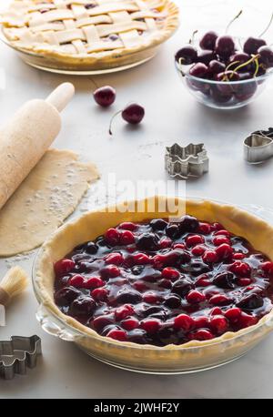 Kirschkuchen zum Backen vorbereiten, vor einem hellen sonnigen Fenster. Stockfoto