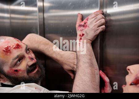 Aggressive Monster versuchen, Aufzug zu entkommen, Angriff Geschäftsbüro, um Menschen zu töten und Gehirn zu essen. Unheimliche, gefährliche, böse Zombies, die besessen und gruselig aussehen, und Wanderer wütend und gory sind. Stockfoto